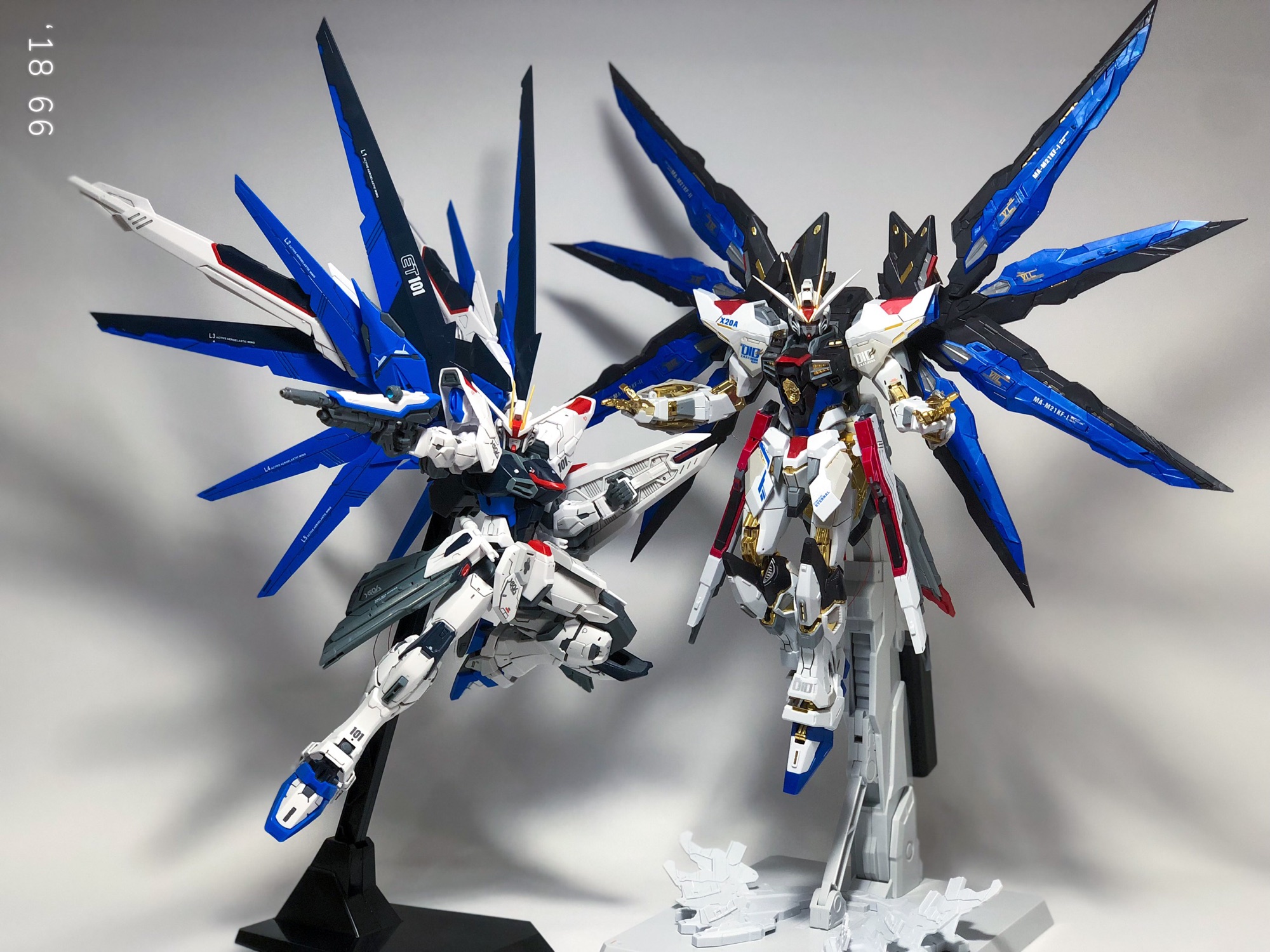 Two blue and white Gundam model kits posed with their wings spread