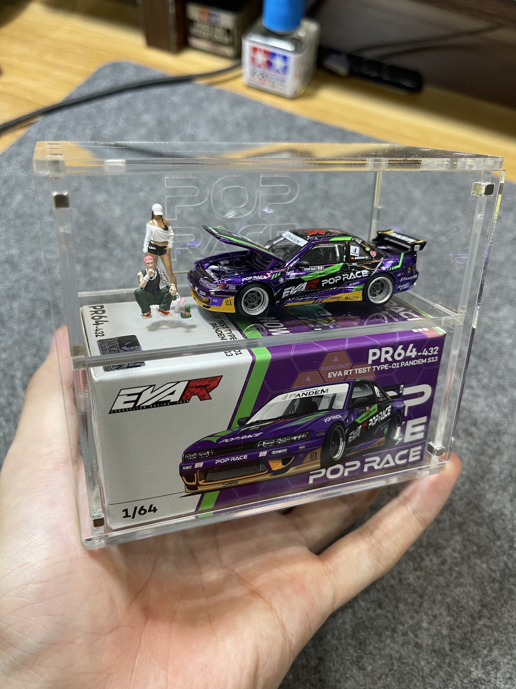 Purple model car with miniature figures in a clear display case